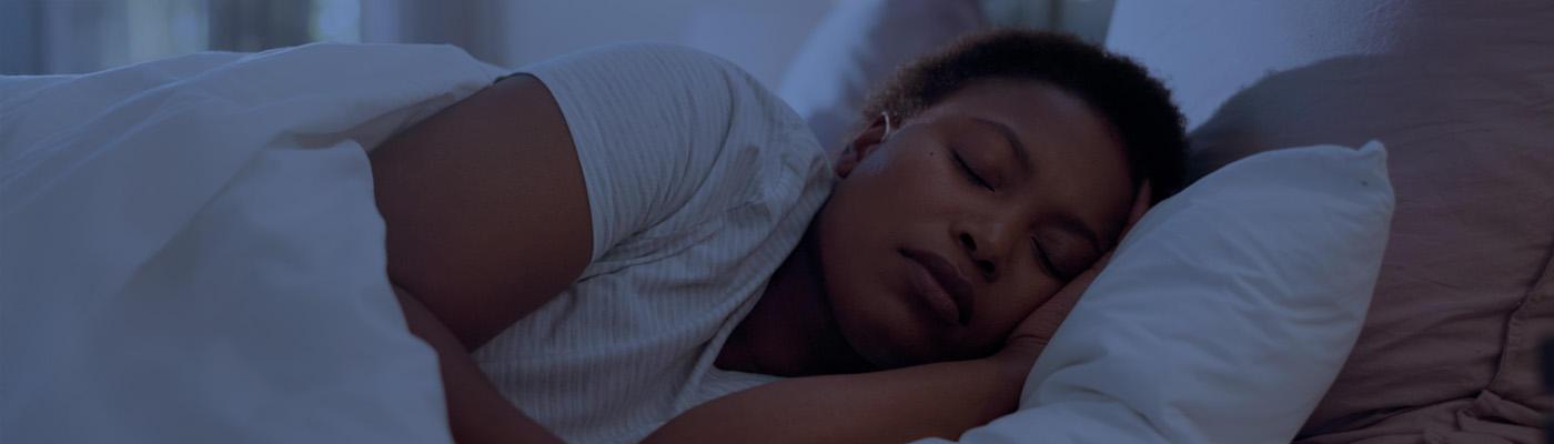 An adult sleeping in their bed