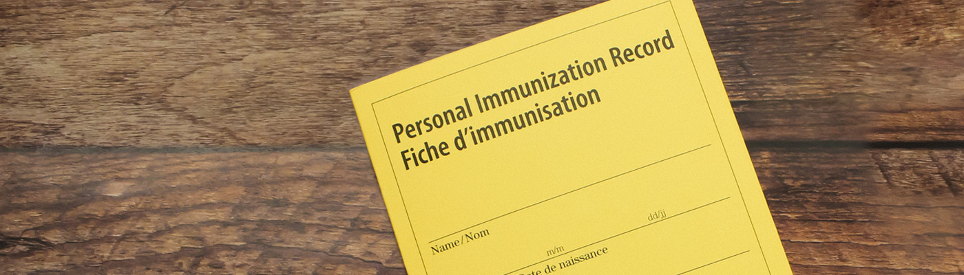 yellow immunization record card on wooden background