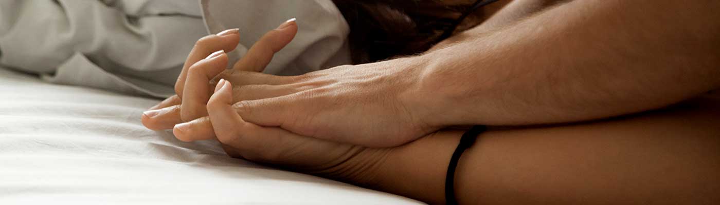 A couple lying in bed holding hands