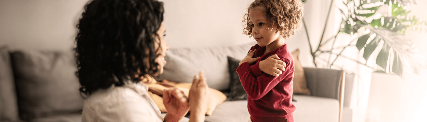 A parent teaching their child head, shoulders, knees and toes in their living room