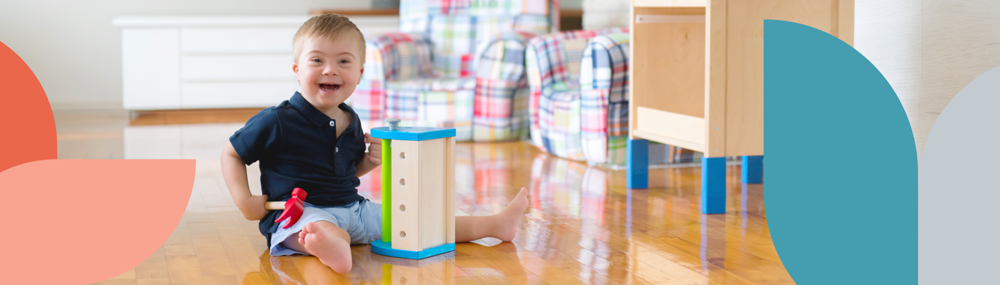 A child playing with a toy hammer and toolbox while sitting on the floor