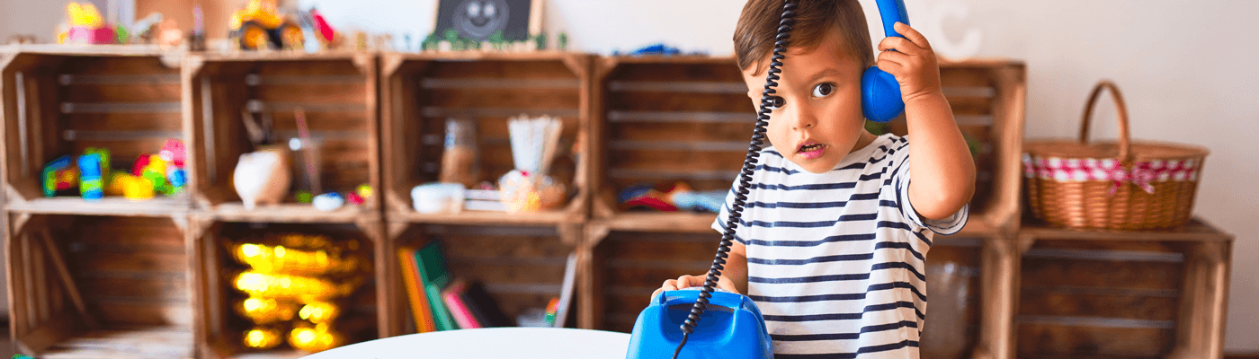 A child pretending to answer a blue telephone